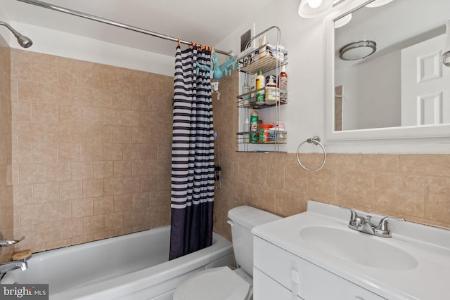 full bathroom with tile walls, vanity, toilet, and shower / bath combo with shower curtain