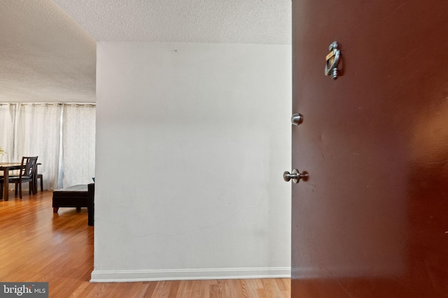 hall featuring light hardwood / wood-style flooring and a textured ceiling