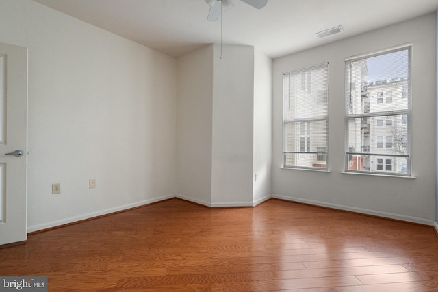 unfurnished room featuring wood finished floors, visible vents, and baseboards