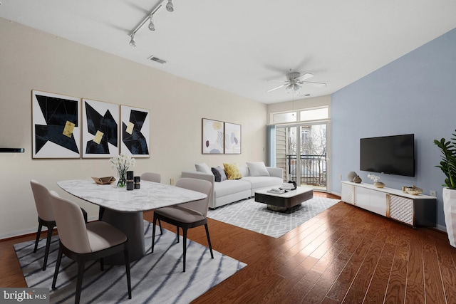 living room with baseboards, visible vents, a ceiling fan, wood finished floors, and track lighting