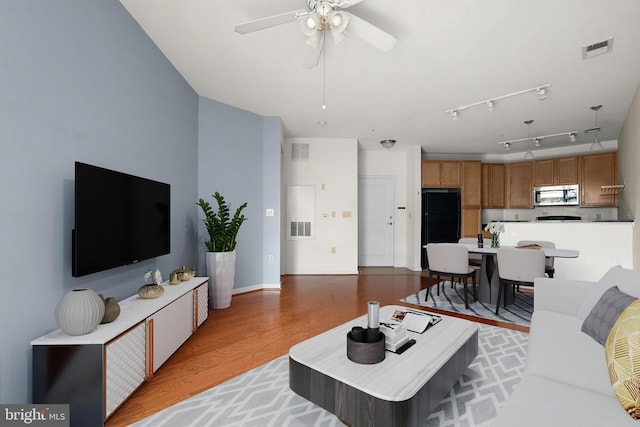 living room featuring light wood-type flooring, ceiling fan, and visible vents