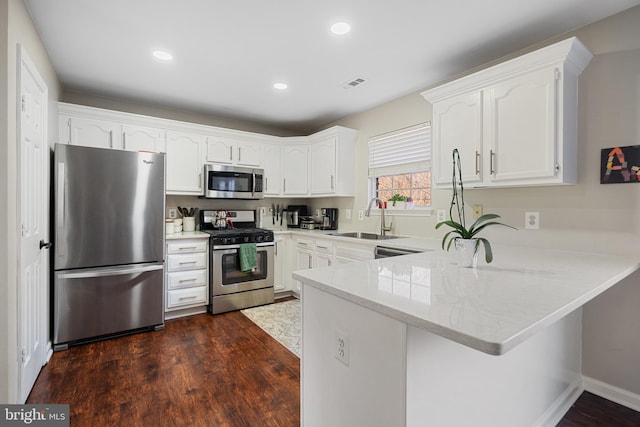 kitchen with sink, white cabinetry, dark hardwood / wood-style floors, kitchen peninsula, and stainless steel appliances