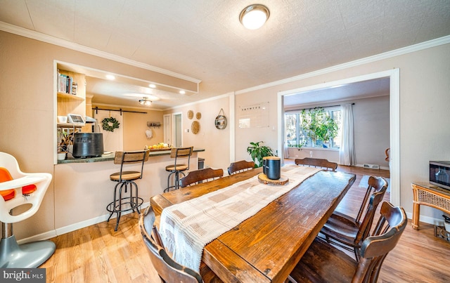 dining space with crown molding and light hardwood / wood-style floors