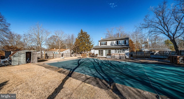 back of property with a storage unit, a covered pool, and a patio area