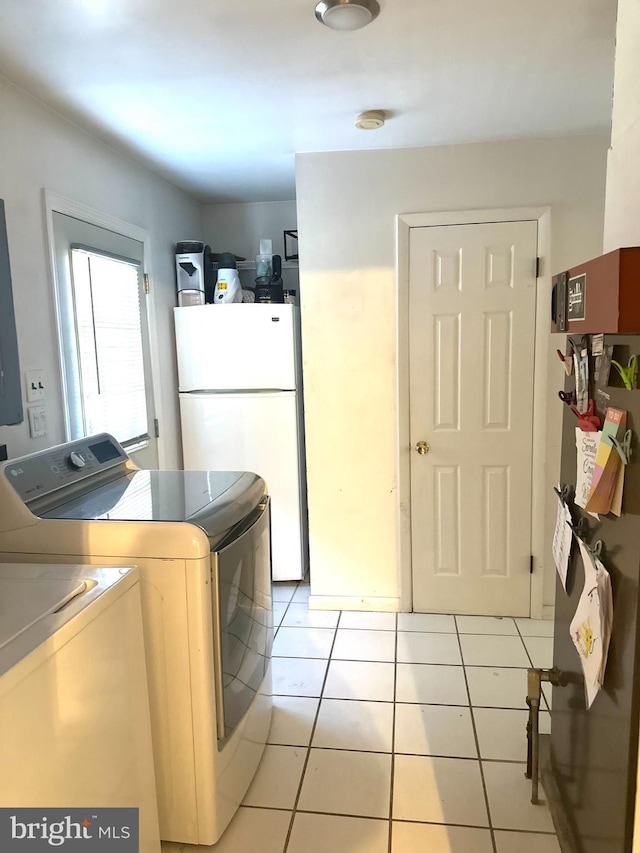 clothes washing area with light tile patterned floors and washer and clothes dryer