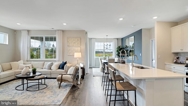 living room featuring sink, dark wood-type flooring, and a notable chandelier