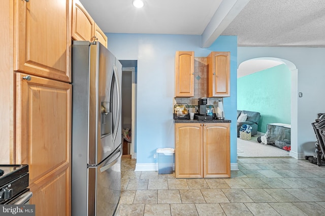 kitchen featuring decorative backsplash, light brown cabinets, and stainless steel refrigerator with ice dispenser