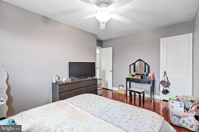 bedroom with ceiling fan, dark wood-type flooring, and a textured ceiling