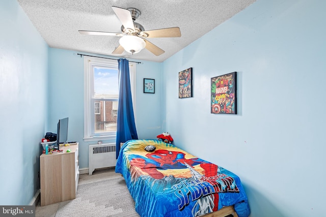 bedroom with ceiling fan, radiator, light carpet, and a textured ceiling