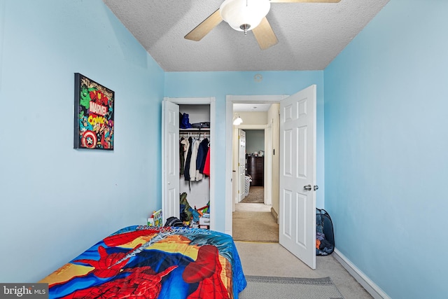 carpeted bedroom featuring ceiling fan, a closet, and a textured ceiling