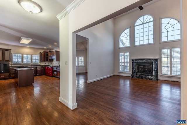 living room featuring dark hardwood / wood-style floors, sink, a high ceiling, a high end fireplace, and crown molding