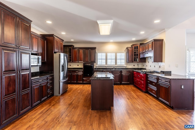 kitchen featuring stainless steel appliances, hardwood / wood-style flooring, a center island, and dark stone counters