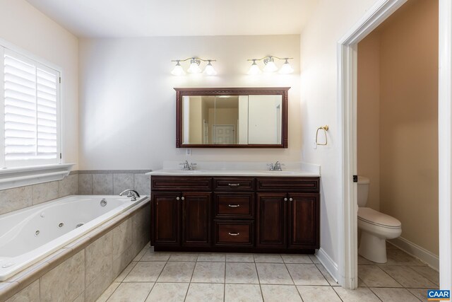 bathroom with tile patterned flooring, vanity, a relaxing tiled tub, and toilet