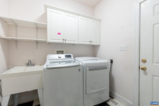 washroom featuring cabinets, sink, and washer and dryer