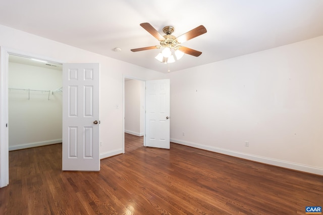 unfurnished bedroom with dark wood-type flooring, ceiling fan, a spacious closet, and a closet