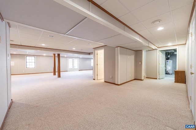 basement featuring a paneled ceiling, light carpet, and water heater