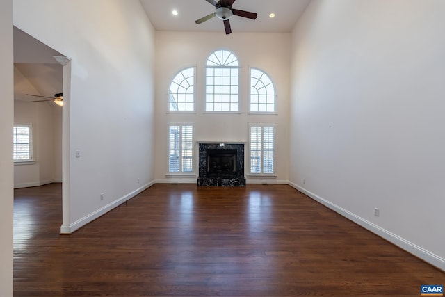 unfurnished living room with dark hardwood / wood-style flooring, a wealth of natural light, and a high end fireplace