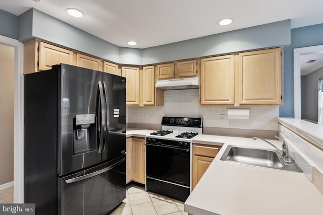 kitchen with sink, light brown cabinets, gas range oven, and black fridge