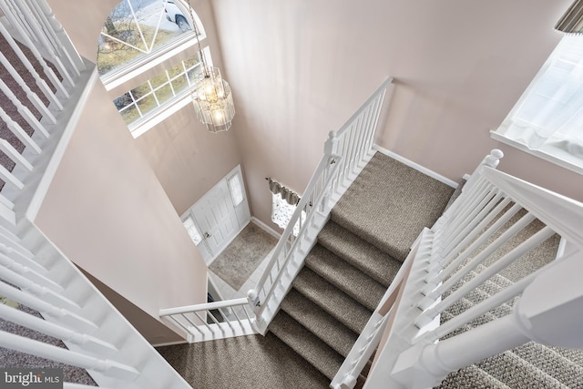 stairway with a high ceiling, carpet, and a notable chandelier