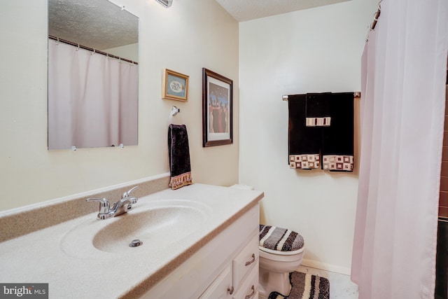 bathroom with vanity, toilet, and a textured ceiling