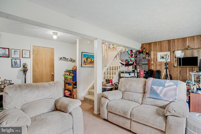 living room with carpet flooring, a textured ceiling, and wooden walls