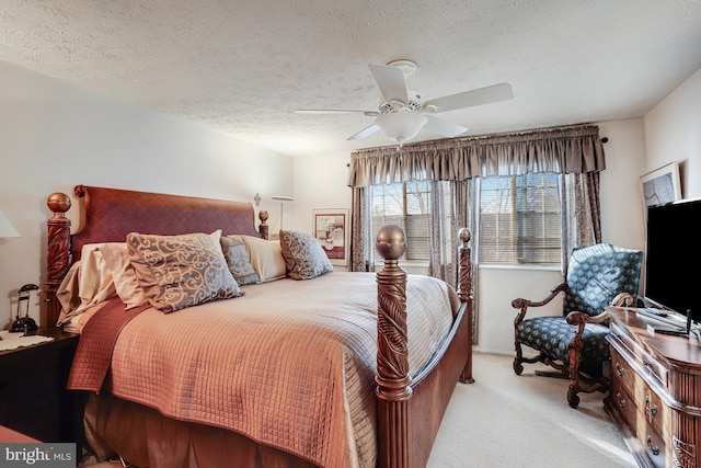 bedroom featuring a textured ceiling, light colored carpet, and ceiling fan