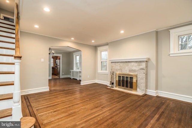 unfurnished living room featuring dark wood-type flooring, ornamental molding, and a wealth of natural light