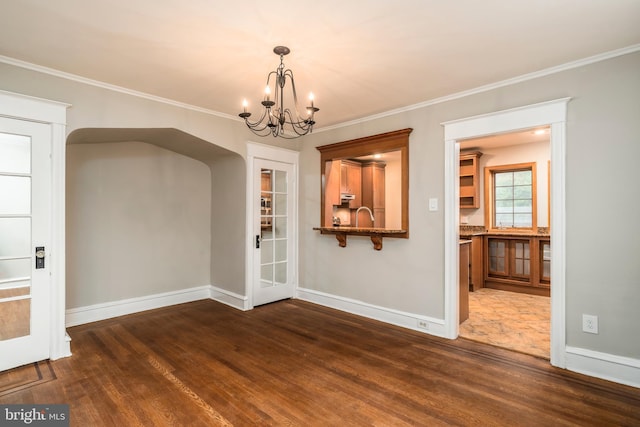 unfurnished dining area featuring ornamental molding, dark hardwood / wood-style flooring, sink, and a notable chandelier