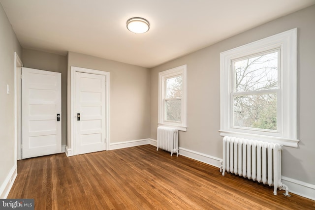 unfurnished bedroom featuring a closet, radiator heating unit, and wood-type flooring