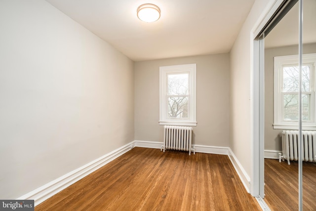 unfurnished room featuring wood-type flooring and radiator