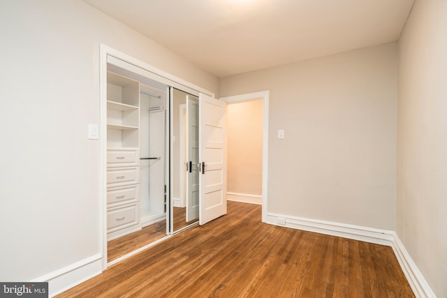 unfurnished bedroom with dark wood-type flooring and a closet