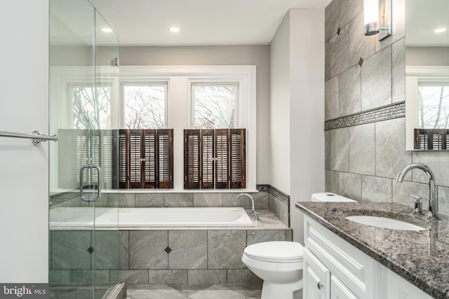 bathroom with a relaxing tiled tub, vanity, and toilet