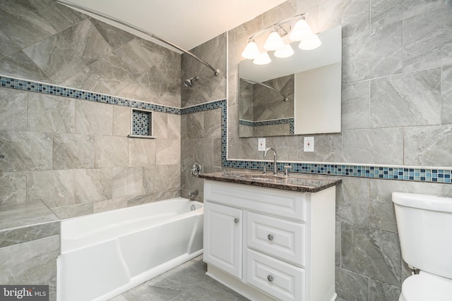 full bathroom with vanity, tiled shower / bath, tile walls, and toilet