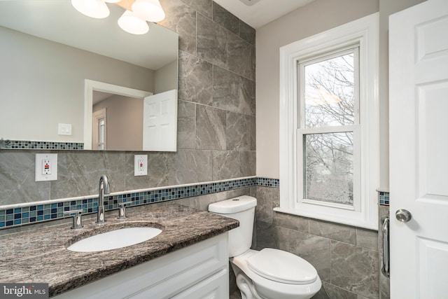 bathroom featuring vanity, tile walls, and toilet