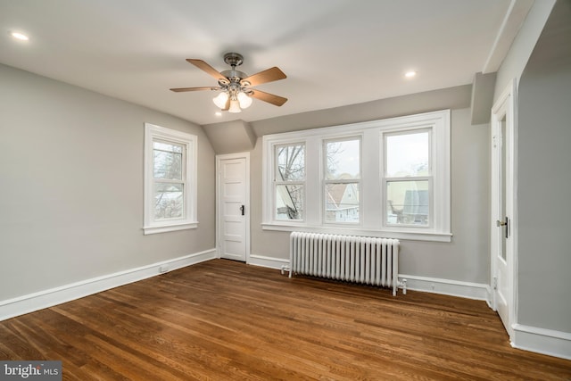 additional living space with ceiling fan, lofted ceiling, radiator heating unit, and dark hardwood / wood-style flooring