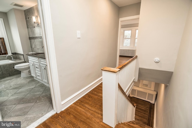 hall featuring dark hardwood / wood-style flooring, sink, and radiator heating unit