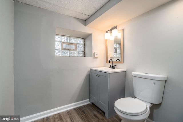 bathroom featuring hardwood / wood-style flooring, vanity, a drop ceiling, and toilet