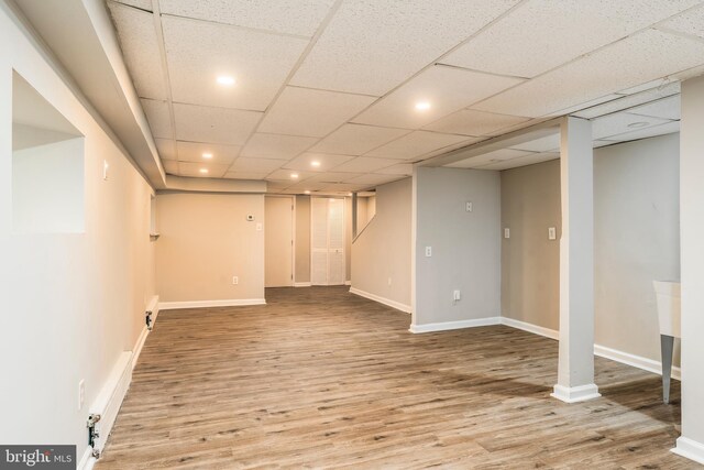 basement featuring a drop ceiling and light hardwood / wood-style floors