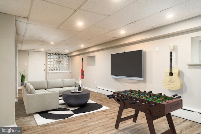 game room featuring a baseboard heating unit, hardwood / wood-style floors, and a drop ceiling