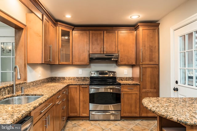 kitchen with stainless steel appliances, light stone countertops, sink, and light tile patterned floors