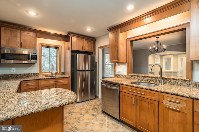 kitchen with pendant lighting, sink, light stone counters, and stainless steel appliances