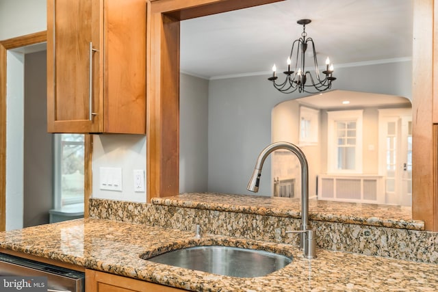 kitchen featuring sink, a chandelier, ornamental molding, stainless steel dishwasher, and light stone countertops