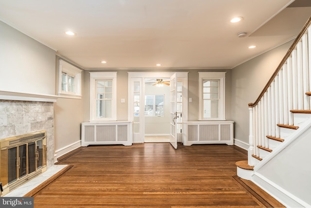 entrance foyer featuring ornamental molding, radiator heating unit, dark hardwood / wood-style floors, and a stone fireplace