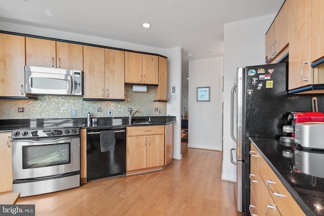 kitchen featuring sink, dark stone countertops, backsplash, stainless steel appliances, and light wood-type flooring