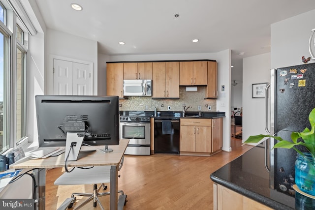 kitchen featuring stainless steel appliances, tasteful backsplash, sink, and light wood-type flooring