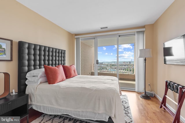 bedroom featuring wood-type flooring, a baseboard heating unit, and access to outside