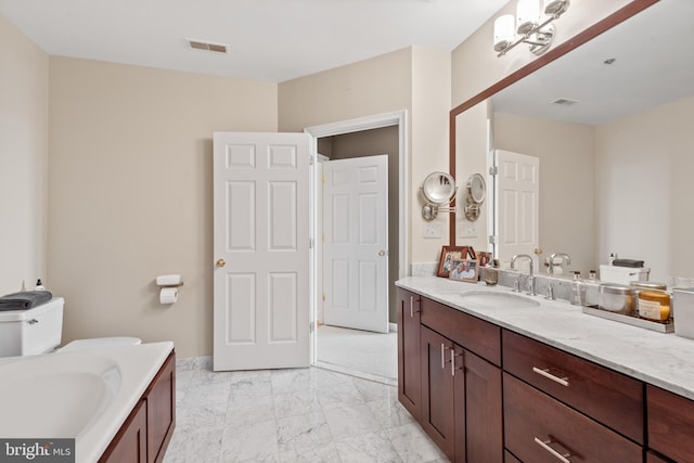 bathroom featuring vanity, a bath, and toilet