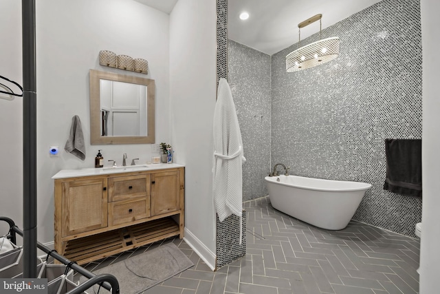 bathroom with a freestanding tub, vanity, and baseboards