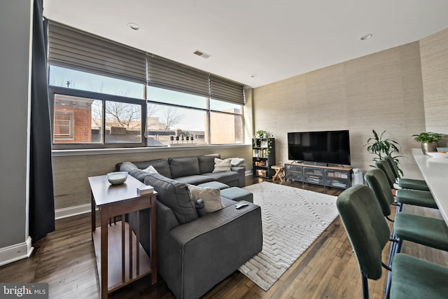 living area with wood-type flooring, visible vents, and baseboards