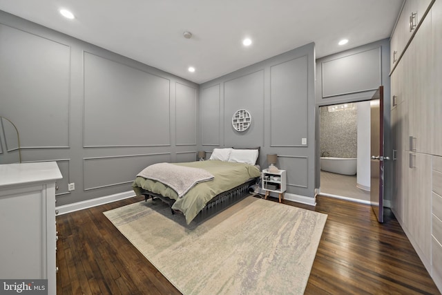 bedroom with a decorative wall, dark wood-style flooring, and recessed lighting